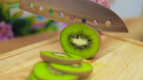 Woman Cuts Kiwi on Wooden Cutting Board