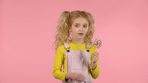 Beautiful Girl with a Lollipop in Studio on Pink Background