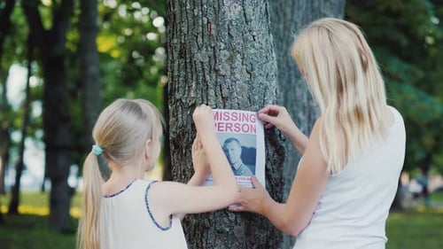A Woman with a Child Is Attached To the Tree Flyer with Information About the Missing Man
