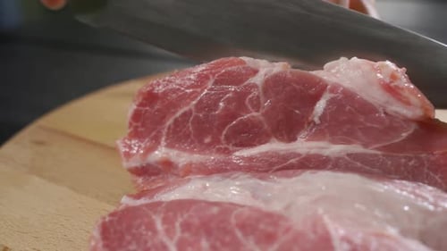 Knife Slices Fresh Red Meat on Cutting Board