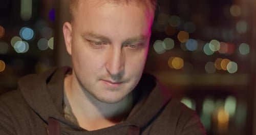 Man Wearing Hoodie Looking Downward at Night