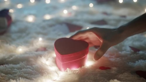 Hand Places Heart-Shaped Gift on Cozy Rug