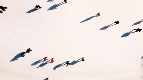 Many People are Skating on White Outdoor Ice Rink in City on Sunny Winter Day