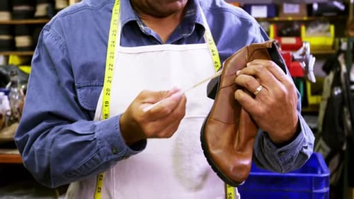 Expert Craftsman Repairing Leather Boot in Workshop
