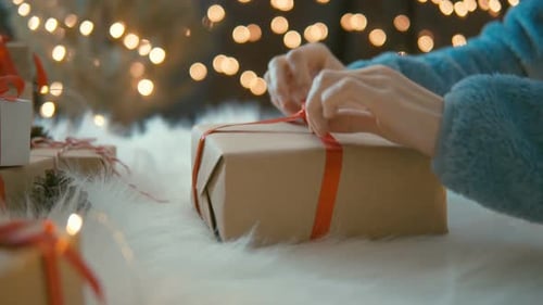 Hands Tying Red Ribbon on Christmas Gift