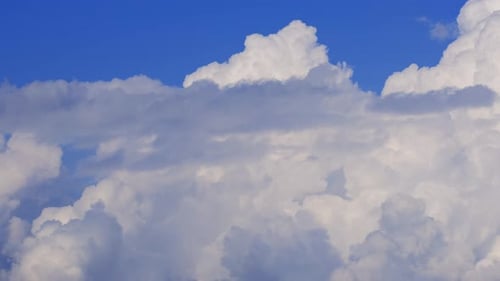 Fluffy White Clouds Drifting Across Blue Sky