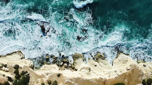 El mar baña la costa rocosa sobre el tiro aéreo que vuela sobre el acantilado de la costa con agua pura azul