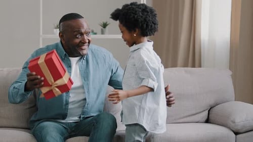 Child Giving Present to Happy Adult on Couch