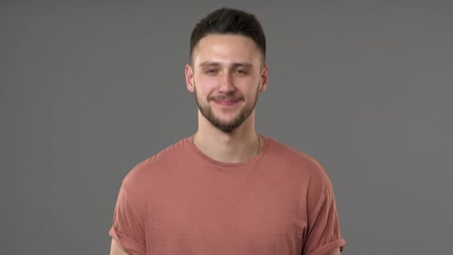 Portrait of Brunette Handsome Guy Having Bristle Nodding and Expressing Approval Isolated Over Gray