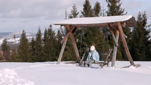 Child on Swing in Snowy Mountain Landscape