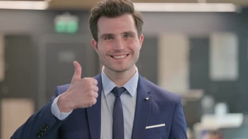 Young Adult Man Giving Thumbs Up in Office