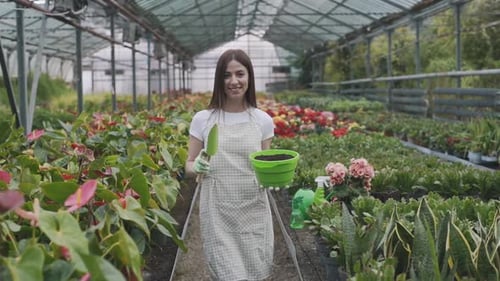 Woman Gardener Smiling in Tropical Greenhouse with Plants