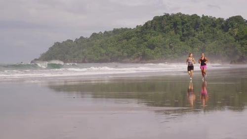 Two friends running on beach together. Shot on RED EPIC for high quality 4K, UHD, Ultra HD resolutio