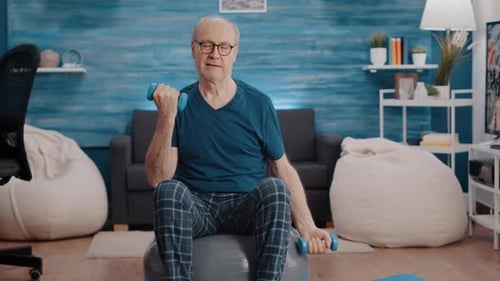 Senior Man Lifting Weights on Exercise Ball