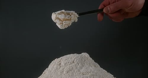 Spoonful of Flour Pouring onto Flour Pile