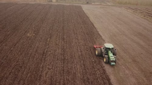 a Large Tractor Plows a Field