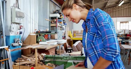 Woman Woodworker Smiling While Holding Wood in Workshop