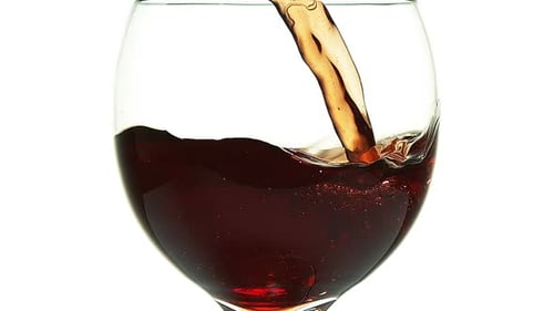Red Wine being poured into Glass, against White Background, Slow motion