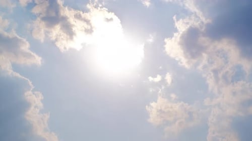 Bright Sun Shining Through Clouds in Blue Sky