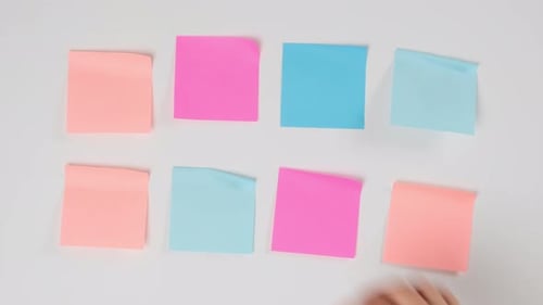 female hand gluing blank square multicolored stickers on white board, business concept