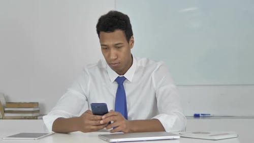 Young Man Using Smartphone at Office Desk