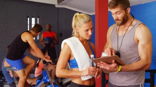 Woman Discusses Workout with Trainer at Gym