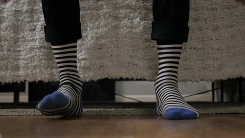 Person with Striped Socks Standing in Bedroom
