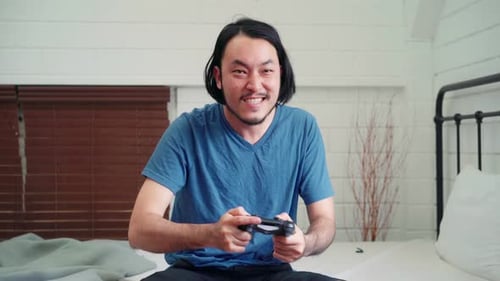 Man Playing Video Game on Bed at Home