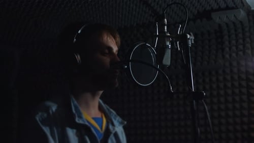 Young man singing into microphone in recording studio