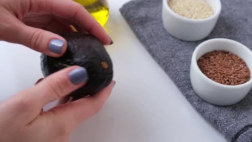 Hands Opening Ripe Avocado next to Cooking Ingredients