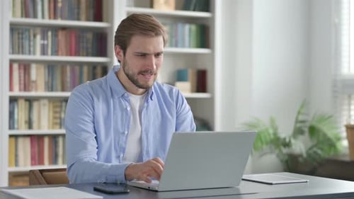 Man Celebrating While Using Laptop in Office on Bench