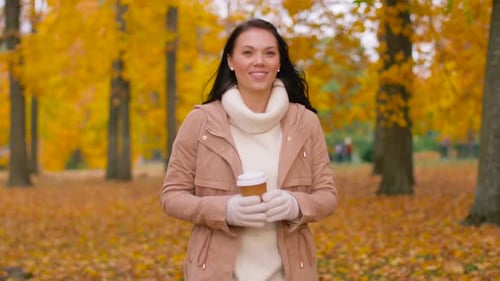 Woman Drinking Takeaway Coffee in Autumn Park