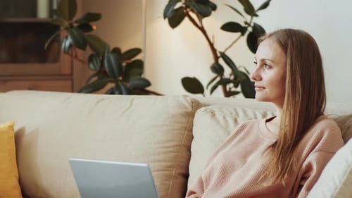Woman Using Laptop Computer on Beige Sofa Indoors