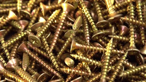 Golden Screws Falling into Pile in Close Up