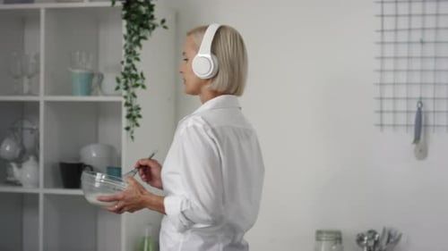 Blonde Woman Mixes Bowl With Whisk in Kitchen