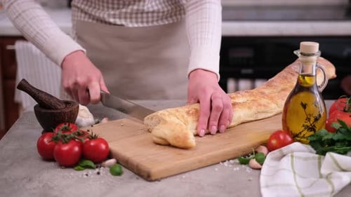Woman Slices Baguette with Fresh Ingredients in Kitchen