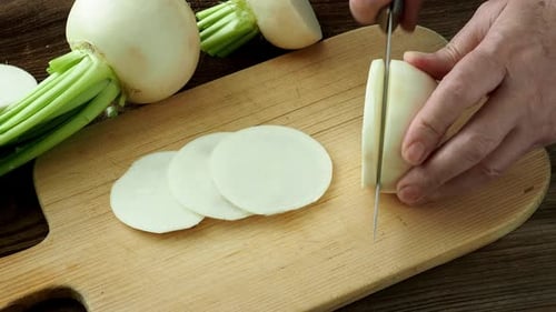 Hands Slicing Turnip Vegetable on a Cutting Board