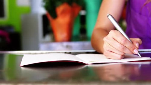 Female florist writing in book