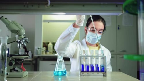 Scientist Uses Pipette with Blue Liquid in Lab
