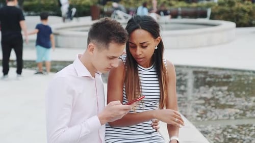 Afrikanische junge Frau ist verärgert, weil ihr Freund ständig ins Smartphone schaut