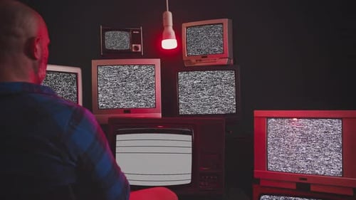 Man Surrounded by Vintage Televisions with Green Screens
