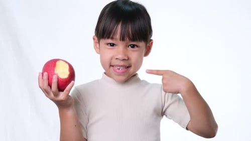Child with Missing Tooth Points to Apple and Smile