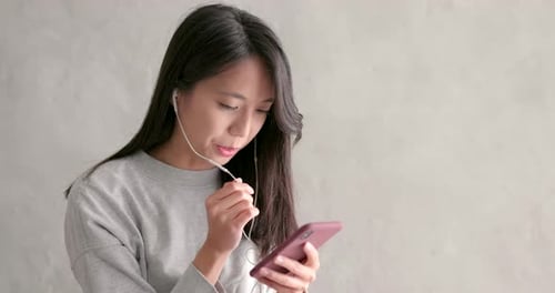 Woman with Smartphone and Earphones Indoors