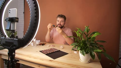 Joven filmando su episodio de videoblog sobre nuevos productos cosméticos mientras