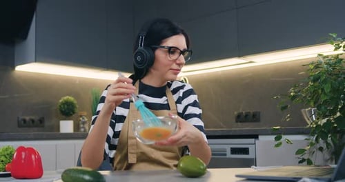 Woman with Headphones Prepares Food in Modern Kitchen
