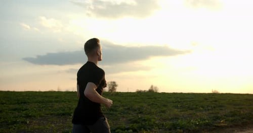 Young Guy Is Running Off-road at Sunset in Autumn Weather