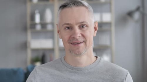 Man Smiles and Waves Hello Indoors