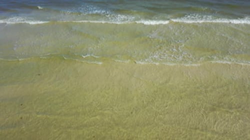 Camera tilts down from the horizon showing the sea to Twenty Twenty written in the sand on a beach.