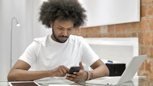 Man Using Smartphone at Desk Indoors