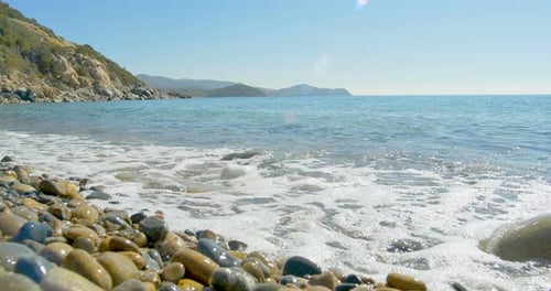 Waves Landing on Stone Beach. Clear Blue Water